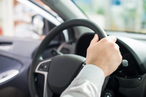 Person holding on to steering wheel in car