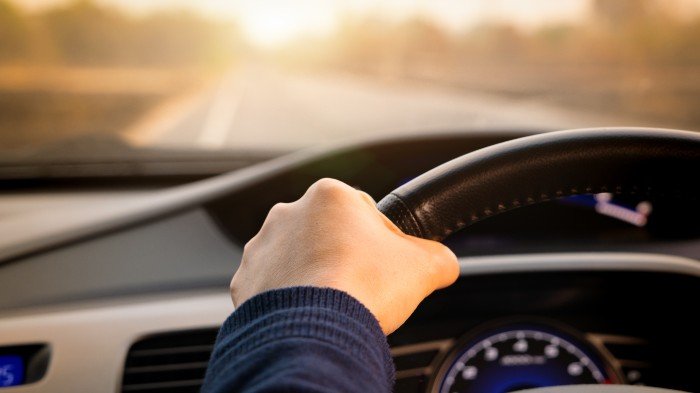 Person driving, close up of holding steering wheel